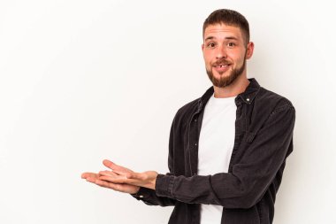 Beyaz arka planda izole edilmiş beyaz tenli genç beyaz bir adam palmiyesinde bir kopya alanı tutuyor..