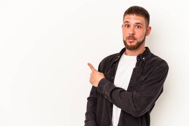 Beyaz arka planda izole edilmiş beyaz tenli genç beyaz adam gülümsüyor ve boş alanda bir şeyler gösteriyor..