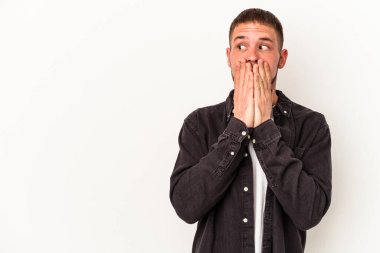 Diasteması olan beyaz tenli genç bir adam beyaz arka planda izole edilmiş. Ağzını eliyle kapatan bir fotokopi odasına bakıyor..