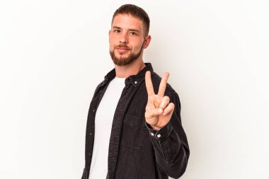Beyaz arka planda izole edilmiş beyaz tenli genç beyaz adam zafer işareti gösteriyor ve gülümsüyor..