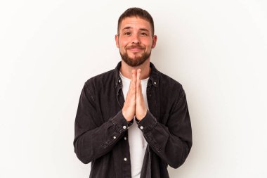 Beyaz arka planda izole edilmiş beyaz tenli genç beyaz bir adam el ele tutuşarak dua ediyor, kendine güveniyor..