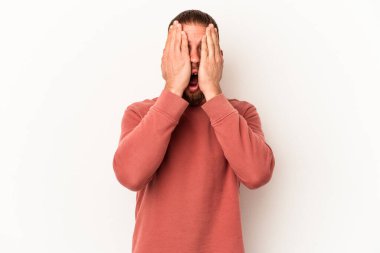 Beyaz arka planda izole edilmiş beyaz tenli genç beyaz adam yüzünün yarısını palmiye ile kaplayarak eğleniyor..