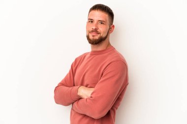 Diasteması olan beyaz tenli genç bir adam beyaz arka planda izole edilmiş, kendinden emin, kararlılıkla kollarını kavuşturuyor..