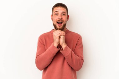 Beyaz arka planda izole edilmiş beyaz tenli genç beyaz bir adam şans için dua ediyor, şaşırıyor ve ağzını açıyor..