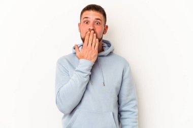 Beyaz arka planda izole edilmiş beyaz tenli genç beyaz adam şok olmuş, ağzı ellerle kaplanmış, yeni bir şey keşfetmeye hevesli..