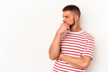 Diasteması olan beyaz bir adam beyaz arka planda izole edilmiş, kafası karışmış, şüpheli ve güvensiz hissediyor..