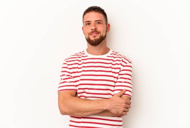 Diasteması olan beyaz tenli genç bir adam beyaz arka planda izole edilmiş, kendinden emin, kararlılıkla kollarını kavuşturuyor..