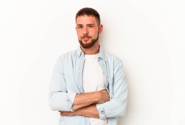 Beyaz arka planda izole edilmiş beyaz tenli genç beyaz adam alaycı bir ifadeyle kameraya bakıyor..