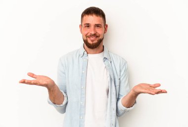 Beyaz arka planda izole edilmiş beyaz tenli genç beyaz adam kollarıyla ölçek oluşturuyor, mutlu ve kendinden emin hissediyor..