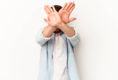 Diastemalı genç beyaz adam beyaz arka planda izole edilmiş iki kolu çapraz tutuyor, inkar kavramı..