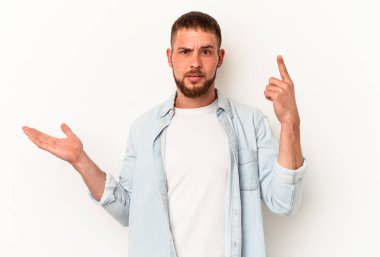 Diastemalı genç beyaz bir adam beyaz arka planda izole edilmiş ve elinde bir ürün var..