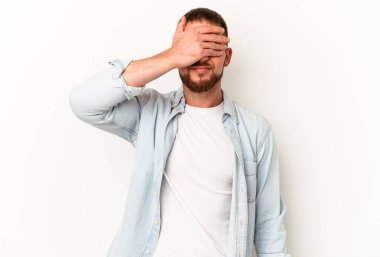 Beyaz arka planda soyutlanmış beyaz tenli genç beyaz bir adam. Gözleri ellerle kaplıyor. Gülümsüyor ve bir sürpriz bekliyor..