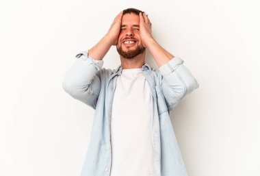 Beyaz arka planda izole edilmiş beyaz tenli genç beyaz adam ellerini başının üstünde tutarak neşeyle gülüyor. Mutluluk kavramı.