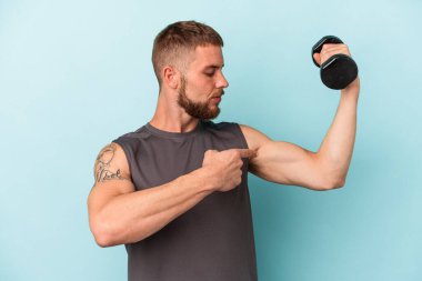 Elinde dambıl tutan genç beyaz adam mavi arka planda izole edilmiş.