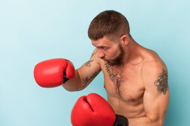 Mavi arka planda tek başına boks yapan beyaz bir genç.
