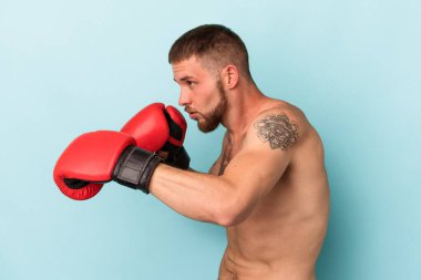 Mavi arka planda tek başına boks yapan beyaz bir genç.