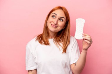 Elinde hijyenik peçete tutan beyaz bir kadın pembe arka planda hedeflerine ve amaçlarına ulaşma hayali kuruyor.