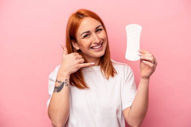 Pembe arka planda hijyenik peçete tutan beyaz bir kadın cep telefonu hareketini parmaklarıyla gösteriyor..