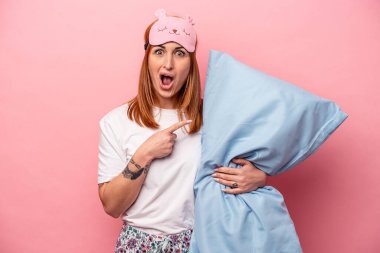 Pembe arka planda izole edilmiş pijama giyen beyaz bir kadın.