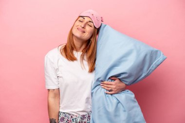 Pembe arka planda izole edilmiş pijama giyen beyaz bir kadın amaçlarına ve amaçlarına ulaşma hayali kuruyor.