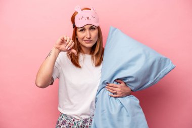 Pembe arka planda izole edilmiş pijama tutan beyaz bir kadın hoş olmayan bir jest yapıyor. Anlaşmazlık konsepti.