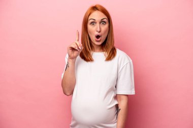 Genç, beyaz, hamile bir kadın pembe arka planda izole edilmiş. Harika bir fikri var. Yaratıcılık kavramı..