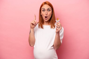 Pembe arka planda emzik tutan beyaz hamile bir kadın. Harika bir fikir, yaratıcılık kavramı var..