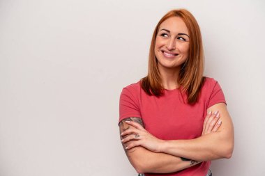 Beyaz arka planda soyutlanmış beyaz bir kadın kollarını kavuşturup gülümsüyor..