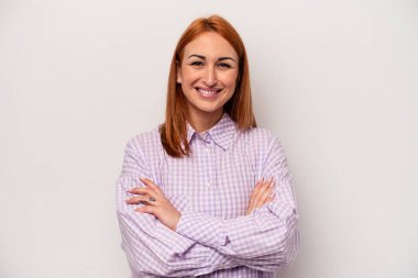Beyaz arka planda kendini güvende hisseden, kararlılıkla kollarını kavuşturan beyaz tenli genç bir kadın..