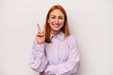 Beyaz arka planda izole edilmiş genç beyaz kadın iki numarayı parmaklarıyla gösteriyor..