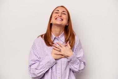 Beyaz arka planda soyutlanmış beyaz tenli genç bir kadın gülüyor, ellerini kalbe koyuyor, mutluluk kavramını koruyor..