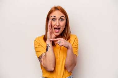 Beyaz arka planda izole edilmiş genç beyaz bir kadın bir dedikodu söylüyor, bir haber sunuyor..