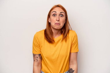 Beyaz arka planda izole edilmiş genç beyaz kadın omuzlarını silker ve gözleri açık kalır..