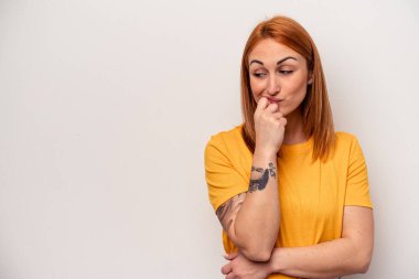 Beyaz arka planda soyutlanmış beyaz tenli genç bir kadın şüpheli ve şüpheci bir ifadeyle yana bakıyor..