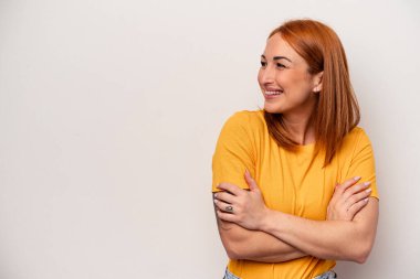 Beyaz arka planda soyutlanmış beyaz bir kadın kollarını kavuşturup gülümsüyor..