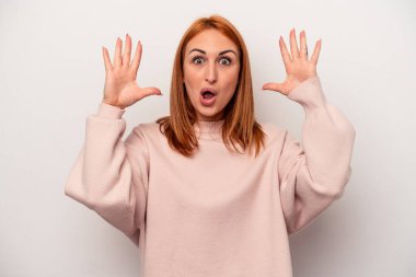 Beyaz arka planda izole genç beyaz kadın zaferi ya da başarıyı kutluyor, şaşırıyor ve şok oluyor..