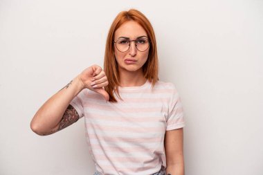 Beyaz arka planda izole genç beyaz kadın baş parmağını aşağı gösteriyor, hayal kırıklığı konsepti.