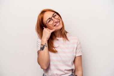 Beyaz arka planda izole edilmiş genç beyaz kadın parmaklarıyla bir cep telefonu hareketi gösteriyor..