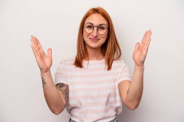 Beyaz arka planda izole edilmiş genç beyaz bir kadın. Elinde parmakları olan, gülümseyen ve kendinden emin bir şey tutuyor..