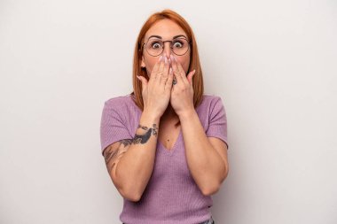 Beyaz arka planda izole edilmiş genç beyaz kadın elleriyle ağzını kapatırken şok oldu..