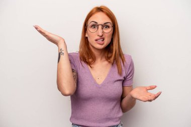 Beyaz arka planda izole edilmiş genç beyaz bir kadın. Kafası karışmış ve omuz silkiyor. Kopya alanını tutmak için..