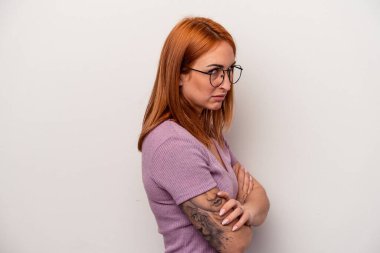 Beyaz arka planda izole edilmiş genç beyaz kadın şüpheli, belirsiz, seni muayene ediyor..