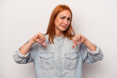 Beyaz arka planda izole genç beyaz kadın baş parmağını aşağı gösteriyor, hayal kırıklığı konsepti.