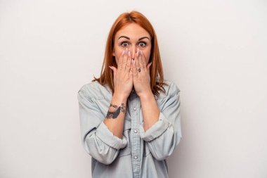 Beyaz arka planda izole edilmiş beyaz tenli genç bir kadın elleri endişeli bir şekilde ağzı örtüyor..