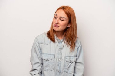 Beyaz arka planda izole edilmiş genç beyaz kadın omuzlarını silker ve gözleri açık kalır..