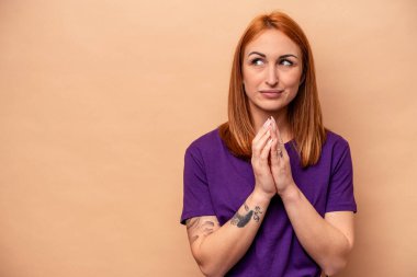 Kafkasyalı genç bir kadın, bej arka planda izole edilmiş, bir plan hazırlıyor..