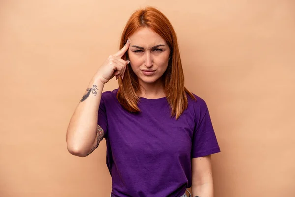 Joven Mujer Caucásica Aislada Sobre Fondo Beige Apuntando Templo Con —  Fotos de Stock