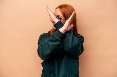 Beyazlı genç bir kadın bej arka planda izole edilmiş iki kolu çapraz tutuyor, inkar kavramı.