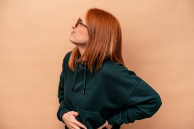 Bej arka planda izole edilmiş beyaz bir kadın sırt ağrısı çekiyor..