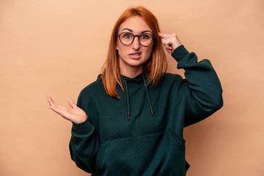 Beyazlı genç bir kadın bej arka planda izole edilmiş ve elinde bir ürün var..